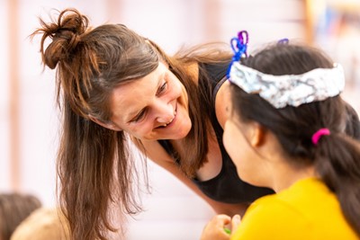 A volunteer engages with young children during a fun, practical workshop.