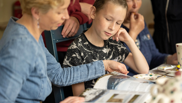 A Ukrainian family and their host family sit around a kitchen table together in Cumbria after receiving support from Cumbria Community Foundation earlier this year.