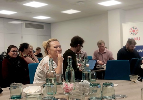 A photo of CEOs sitting at round tables in a conference room looking forwards to the front of the room with interest.