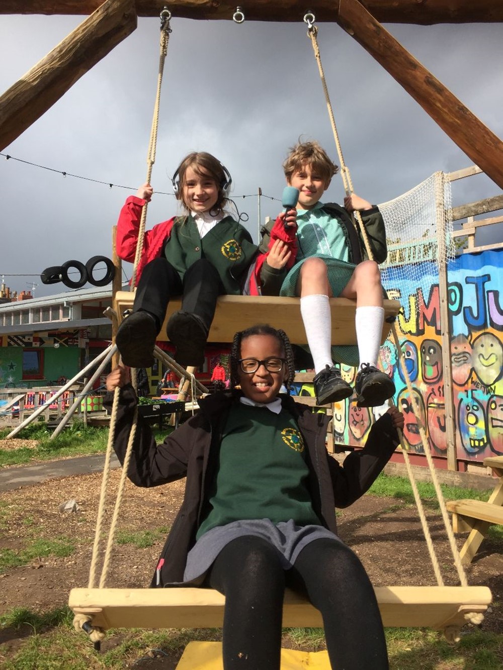 three girls on a swing in the playground