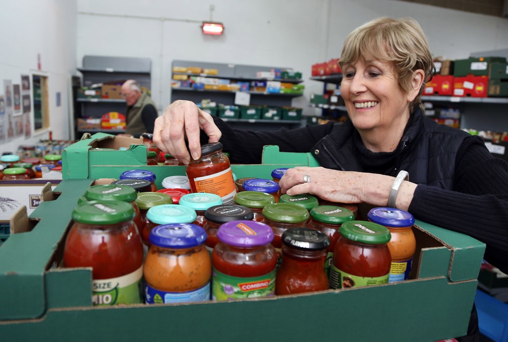 Woman smiling sorting jars in a community food pantry
