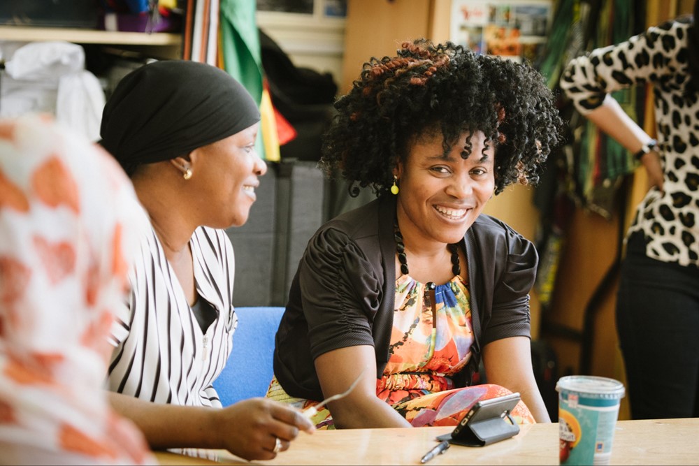 Two women sitting talking with one looking at the camera