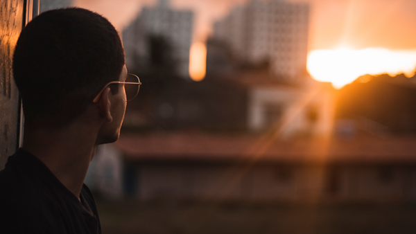 Young person looking at sunrise over a city