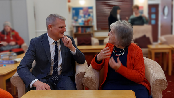 Minister for Civil Society and youth, Stuart Andrew, sits next to an elderly befriending service member at Age UK Hull, deep in discussion.