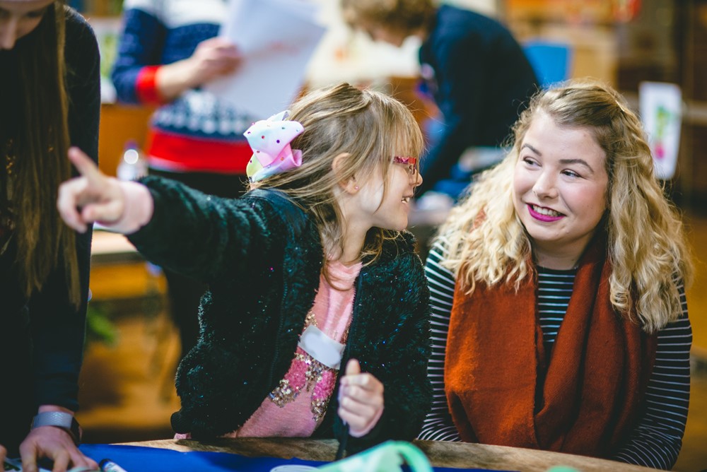 Little girl pointing and looking at women, with women looking in the direction the girl is pointing